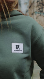 Zoom sur l'étiquette brodée et la maille épaisse du sweat à capuche vert bio